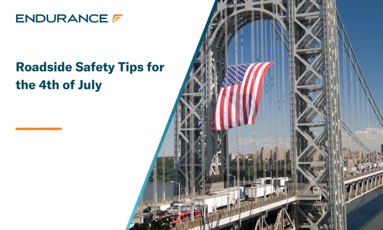 Large American flag flying on a busy bridge with traffic